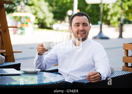 Confident successful businessman in suit enjoying a cup of coffee while having work break lunch in modern restaurant,young intelligent man or entrepreneur relaxing in outdoors cafe looking pensive Stock Photo