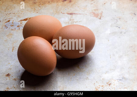 three raw uncooked eggs on a steel plate Stock Photo