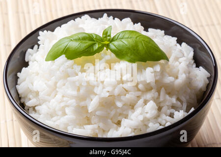 cooked rice whit basil in black bowl Stock Photo