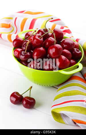 Ripe sweet cherries in a green colander on white background,selective focus Stock Photo