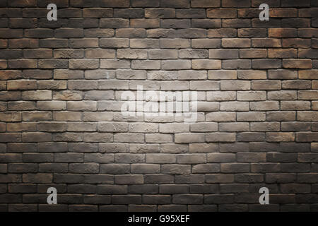 dark black brown gray brick wall background with light gradient circle in the middle Stock Photo