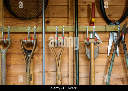 Garden tools hanging in a wooden shed. Stock Photo