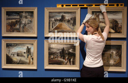 Emma Shaw, of the Royal Collection, holds a spirit level over some paintings from a collection by the artist John Piper. The paintings of Windsor Castle were commissioned by the Queen Mother in 1942 and form part of an exhibition of works by British artists from her personal collection which is to go on display at Buckingham Palace. Stock Photo