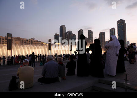 Spectators watching the water display of the Dubai Fountain on Burj Khalifa Lake at dusk, Downtown Dubai, United Arab Emirates Stock Photo