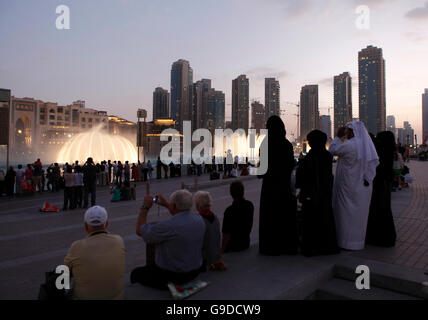 Spectators watching the water display of the Dubai Fountain on Burj Khalifa Lake at dusk, Downtown Dubai, United Arab Emirates Stock Photo