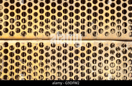 Orange rusted ventilation grill with many circular holes used as airflow for radiators on industrial machines and vehicles. Stock Photo