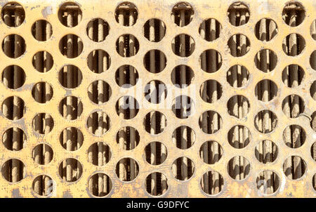 Orange rusted ventilation grill with many circular holes used as airflow for radiators on industrial machines and vehicles. Stock Photo