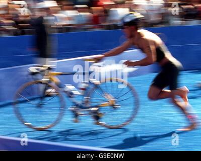 A triathlete pushes his cycle out of the transition area having completed the swim in Sydney Harbour Stock Photo