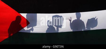 Protesters silhouetted behind the national flag of Palestine during a protest over the violence in the middle east, outside the National Galleries in Edinburgh. Stock Photo