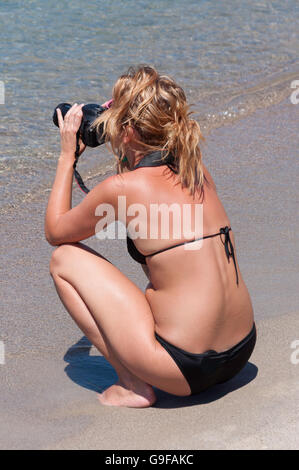 Young woman taking photos on the beach, Pserimos Town, Pserimos, The Dodecanese, South Aegean Region, Greece Stock Photo