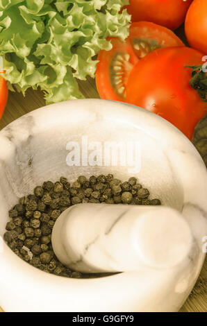 Marble mortar with pepper and vegetables on wooden table Stock Photo