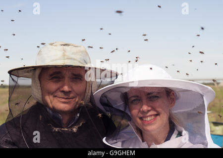 horizontal portrait of two beekeepers, father and daughter, surrounded by swarmming bees Stock Photo