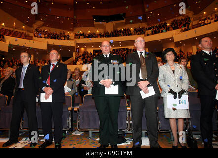 Paul Goggins, Northern Ireland Security Minister (second left), with Assistant Chief Constable Paul Leighton of the PSNI (centre), and Lady Carswell OBE, Lord Lieutenant of Belfast (second right) as Petals of Remembrance fall on the auditorium during a commemoration service in memory of police officers killed at the Waterfront Hall in Belfast. Stock Photo