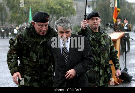 Defence Minister Willie O'Dea runs for cover during heavy rainfall as he reviews the 33rd Infantry Group bound for overseas service with Kosovo Force (Kfor) at a parade in Cathal Brugha Barracks, Dublin. Stock Photo