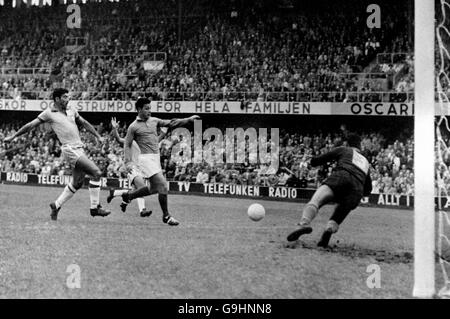 France's Juste Fontaine (c) bursts through as Brazil goalkeeper Gilmar (r) dives to save and Brazil's Nilton Santos (l) looks on Stock Photo