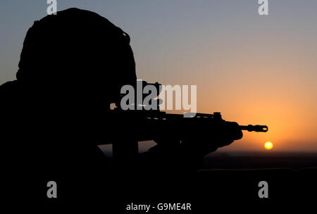 The sun sets as a Royal Marine stands guard in the watchtower at FOB Prise near Gereshk in Afghanistan. Stock Photo