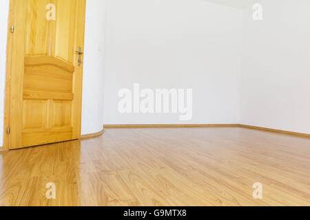 empty room with white walls and wooden laminate and open wooden door Stock Photo