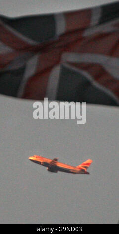 A British Airways plane flies past the Union Jack above Parliament in London. Stock Photo