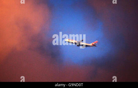 A British Airways plane flies past past a gap in the clouds above London. Stock Photo