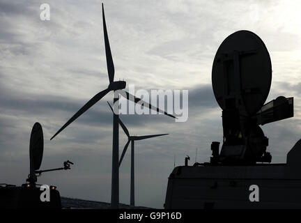 Satellite dishes on television trucks are seen sillhouetted next to a wind turbine as Trade and Industry Secretary Alistair Darling (not pictured) officially opens the Braes of Doune windfarm near Stirling, Scotland. Stock Photo