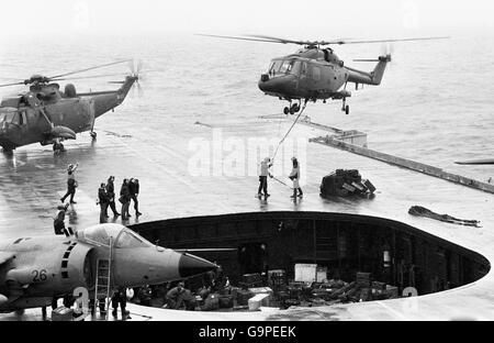 Small arms ammunition and stores from HMS Brilliant are air-lifted aboard HMS Hermes by Lynx helicopters in misty conditions, during the Falklands conflict. Stock Photo