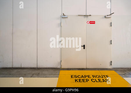 Emergency exit door with keep clear warning message on floor, copy space on wall Stock Photo