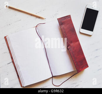 Top view of notepad, smartphone and pencil on marble background Stock Photo