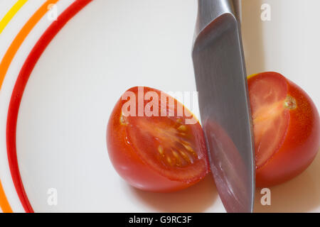 A single red tomato sliced open with a knife Stock Photo