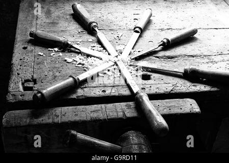 series of many sharp steel blades many chisels and sawdust chippings in an old Workbench Stock Photo