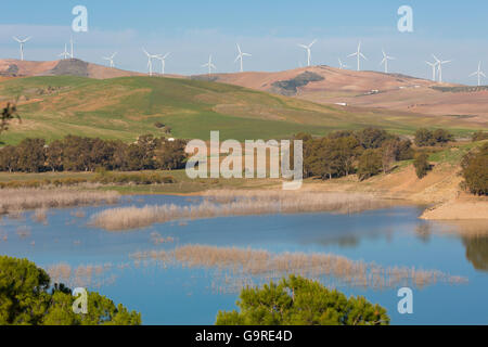 View across Guadalhorce dam, Malaga Province, Andalusia, Spain, to farmland and wind turbines beyond. Stock Photo