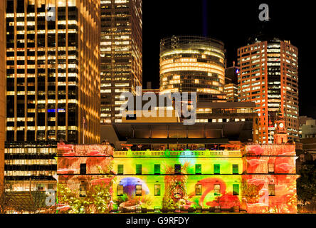 Bright illuminated skyscraper towers of Sydney city at night around historic customs house in Circular quay area of CBD. Stock Photo