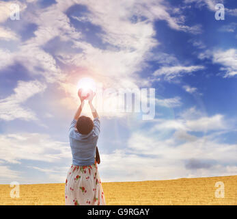 Women rare or back view gently raise red heart to puffy clouds blue sky in sunlight with love, careness and restpect on wild gra Stock Photo