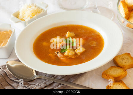 A plate of French fish and seafood soup, served with toast, rouille sauce and grated cheese Stock Photo