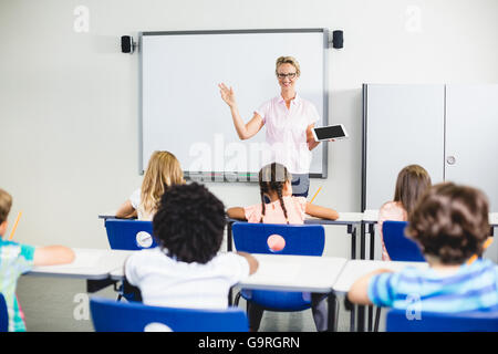 Teacher teaching kids on digital tablet Stock Photo