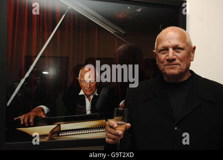 Steven Berkoff stands next to his portrait depicting his childhood dream of 'being a pianist', at the 'When I Grow Up' photographic exhibition - held by the Children's Society - in central London. Stock Photo