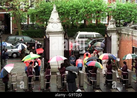 Gate stewards and fans shelter under their umbrella's as rain falls at Lords delaying the start of play on the first day Stock Photo