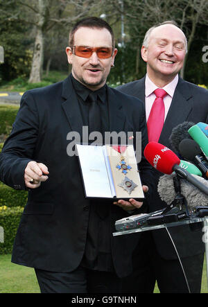 Bono, with the British Ambassador David Reddaway (right), speaks to the media outside the British ambassador's official residence in Sandyford, Dublin.after he was given his honorary knighthood. Stock Photo