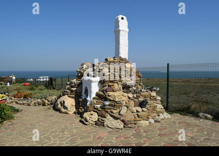 Outdoors whitewashed stove high chimney, lined with pebbles and shell stone. Decorated stone Russian stove for cooking food on t Stock Photo