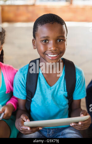 Smiling schoolboy using digital tablet at school Stock Photo