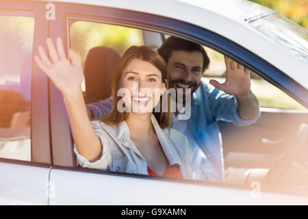 Happy couple waving hands while in car Stock Photo