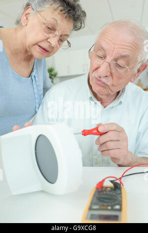 elderly man fixing a coffee machine Stock Photo