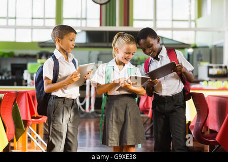 School kids using digital tablet in school cafeteria Stock Photo
