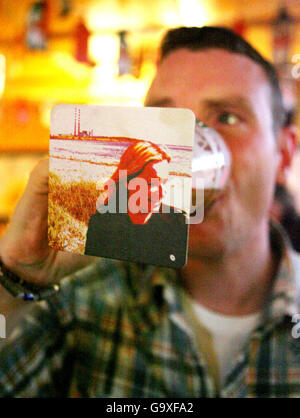 A Man drinks a pint in Dublin with a beer mat of Fine Gael candidate Lucinda Creighton stuck to his glass. Stock Photo