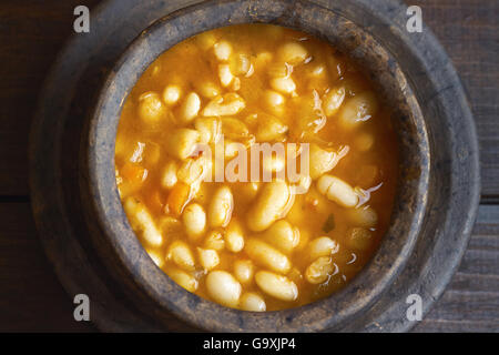 Cooked beans served in clay bowl on dark wooden background. Top view Stock Photo