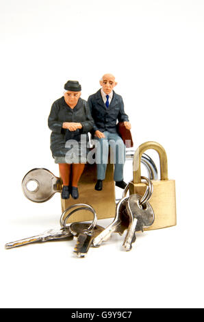 Miniature figurines of elderly couple sitting on padlocks Stock Photo
