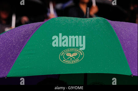 London, UK. 2nd July, 2016. A spectator waits under an umbrella after rain stopped the match between Venus Williams of the United States celebrates her victory over Daria Kasatkina of Russia during their women's singles third round match at the Wimbledon Tennis Championships in London, Britain. Credit:  Han Yan/Xinhua/Alamy Live News