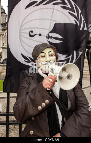 Belfast, UK, Europe. 4th July 2016. A woman wearing a Guido Fawkes/Anonymous mask with an Anonymous Flag tied to the gates of Belfast City hall where protesters staged a rally Credit:  Bonzo/Alamy Live News Stock Photo