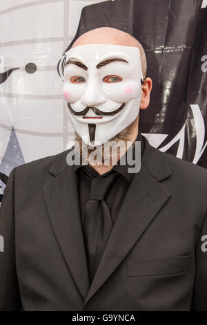 Belfast, UK, Europe. 4th July 2016. A man in a Guido Fawkes/Anonymous mask with an Anonymous flag in the background where protesters staged a rally at the gates of Belfast City hall. Credit:  Bonzo/Alamy Live News Stock Photo