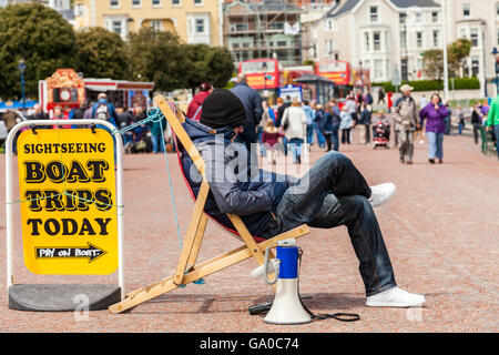 Man deep in thought with hands in pocket sitting on deck chair with megaphone down by his side.  Llandudno Wales Great Britain Stock Photo