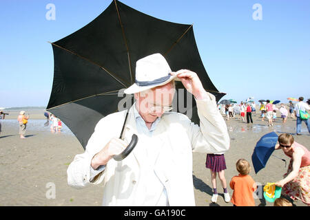 PHOTO Green Party Deputy Leader and member of the Government Forming talk team with Fianna Fail, John Gormley TD tries to cover up with his hat and umbrella at the Umbrella Action Day against climate change on Sandymount Strand, Dublin. Stock Photo